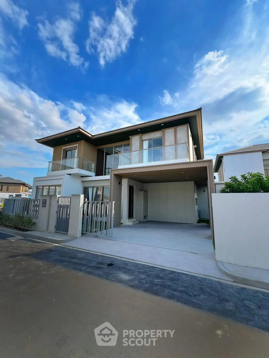 Modern two-story house with spacious driveway and contemporary design under a clear blue sky.