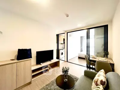 Modern living room with open layout, featuring sleek furniture and a view into a cozy bedroom.