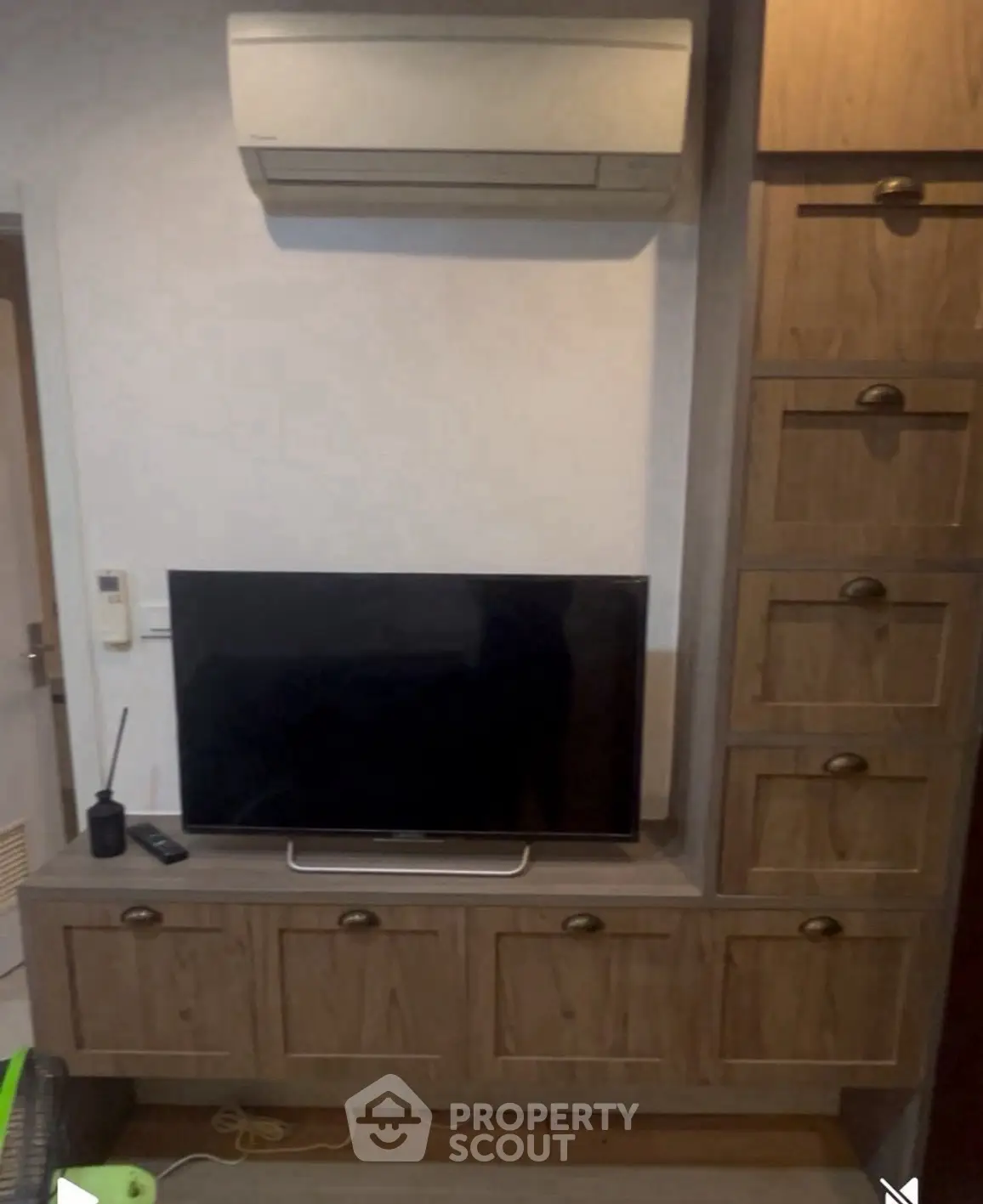 Cozy living room with built-in wooden TV cabinet and air conditioning unit.