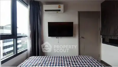 Modern bedroom with air conditioning and wall-mounted TV, featuring large windows for natural light.