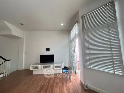 Spacious living room with modern TV setup and large windows for natural light.