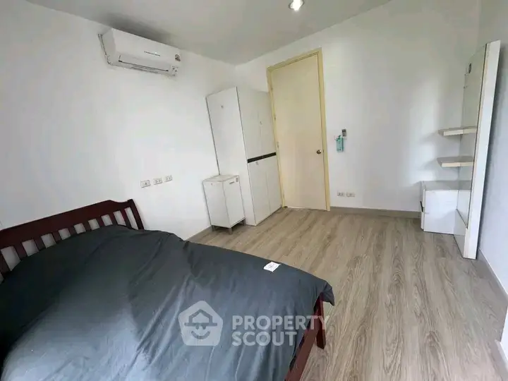 Spacious bedroom with modern furnishings and wooden flooring, perfect for comfortable living.