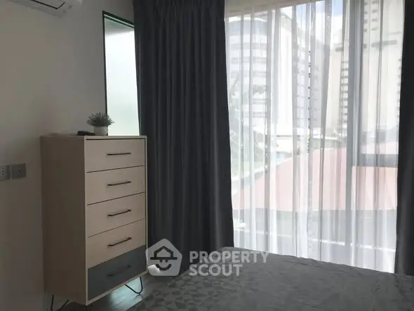 Modern bedroom with large window and stylish curtains in urban apartment.