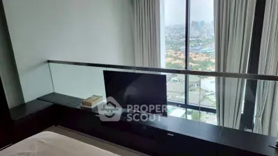 Modern bedroom with city view, featuring sleek TV setup and floor-to-ceiling windows.