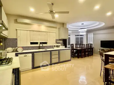 Spacious modern kitchen with open layout and dining area, featuring sleek cabinetry and ambient lighting.