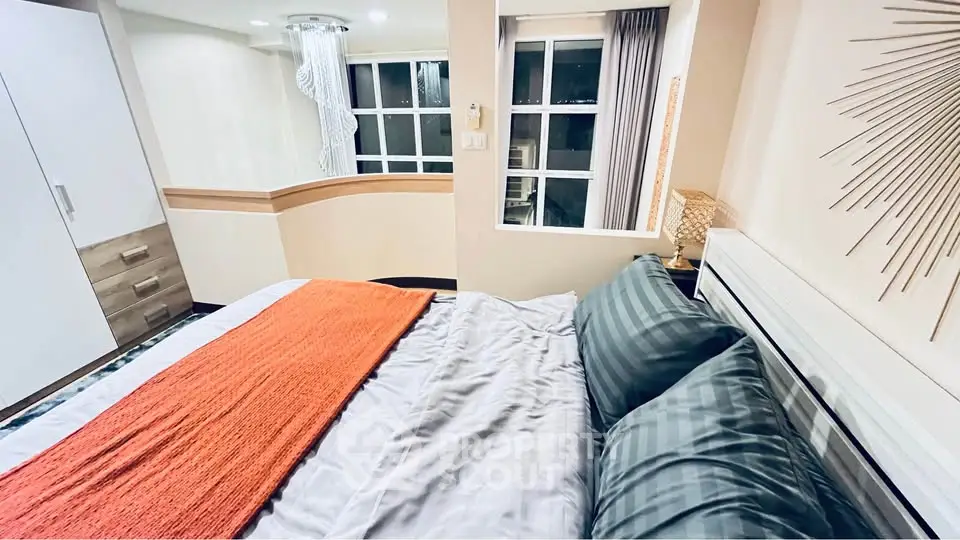 Modern bedroom with stylish decor and large window offering natural light.