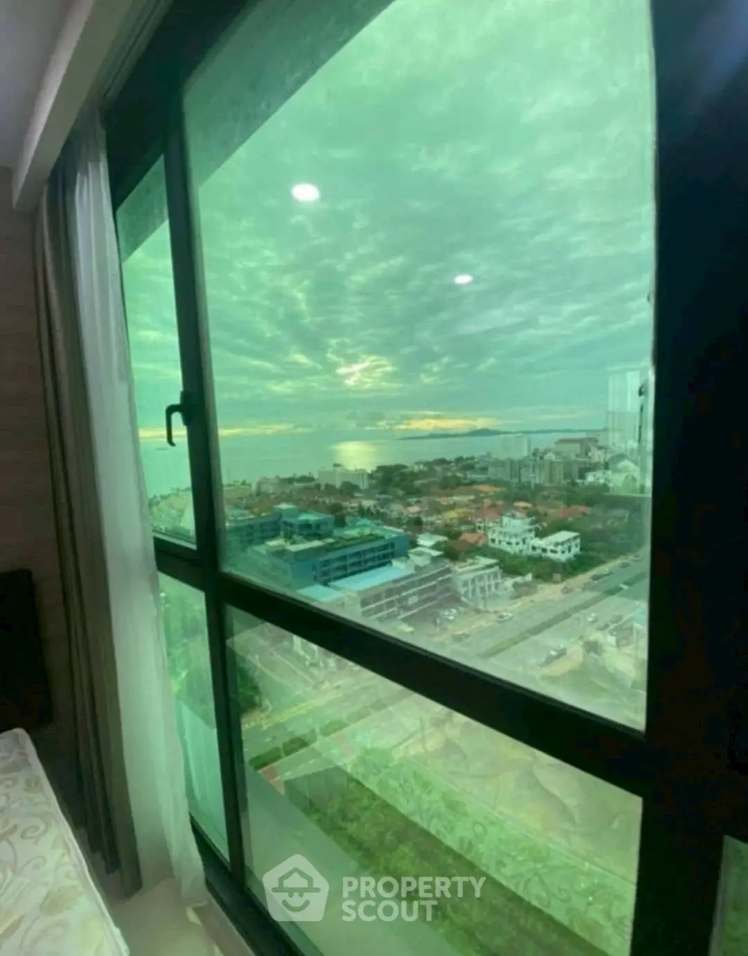 Stunning high-rise view from a modern apartment window overlooking cityscape and ocean.