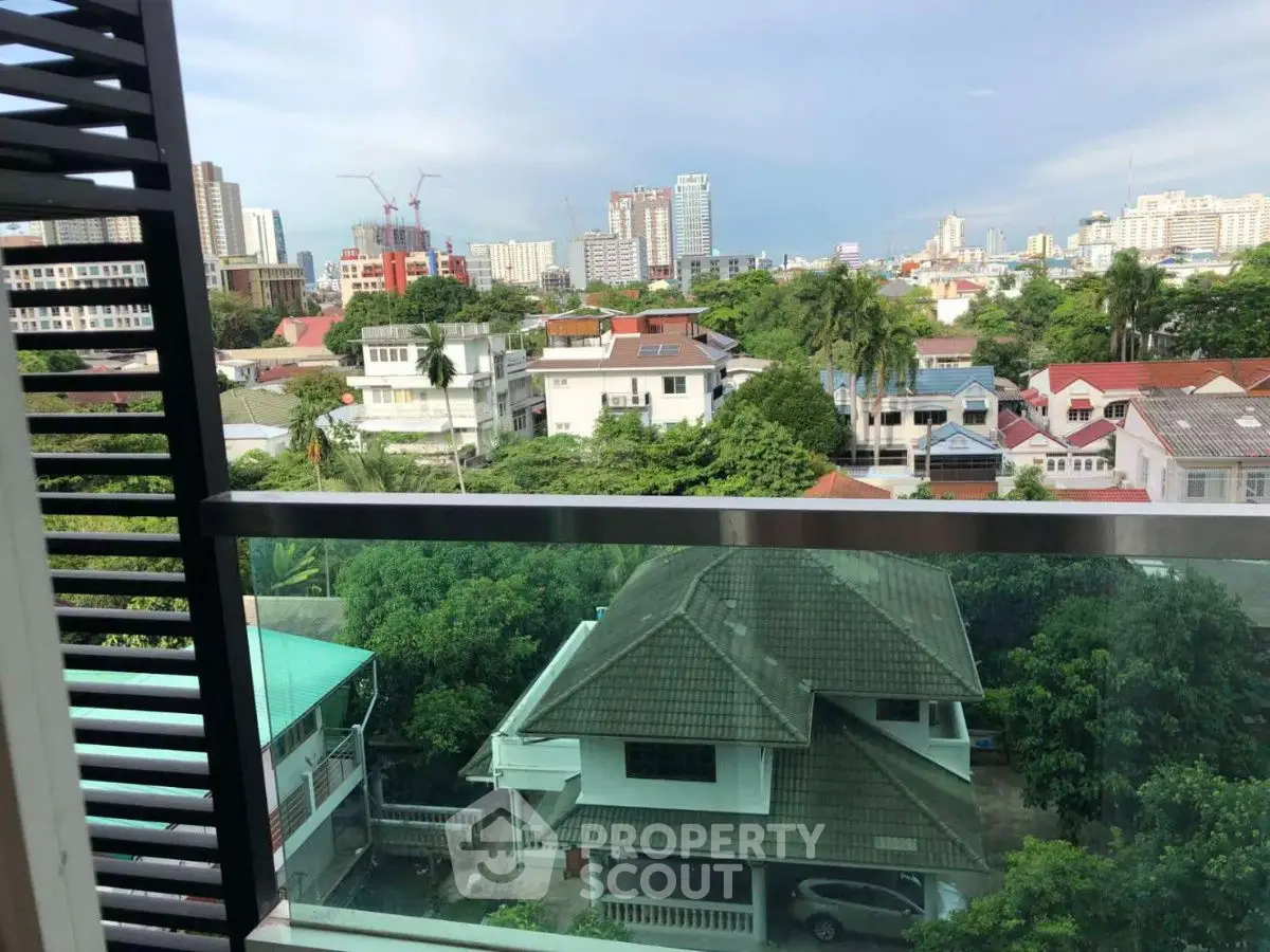 Stunning cityscape view from a modern balcony overlooking lush greenery and urban skyline.