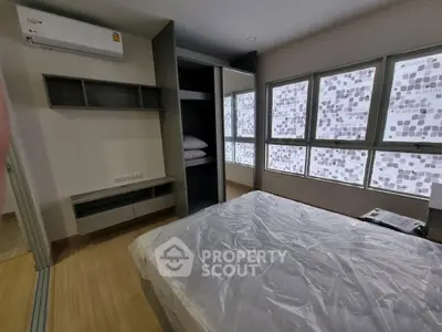 Modern bedroom with large windows and built-in storage in a stylish apartment.