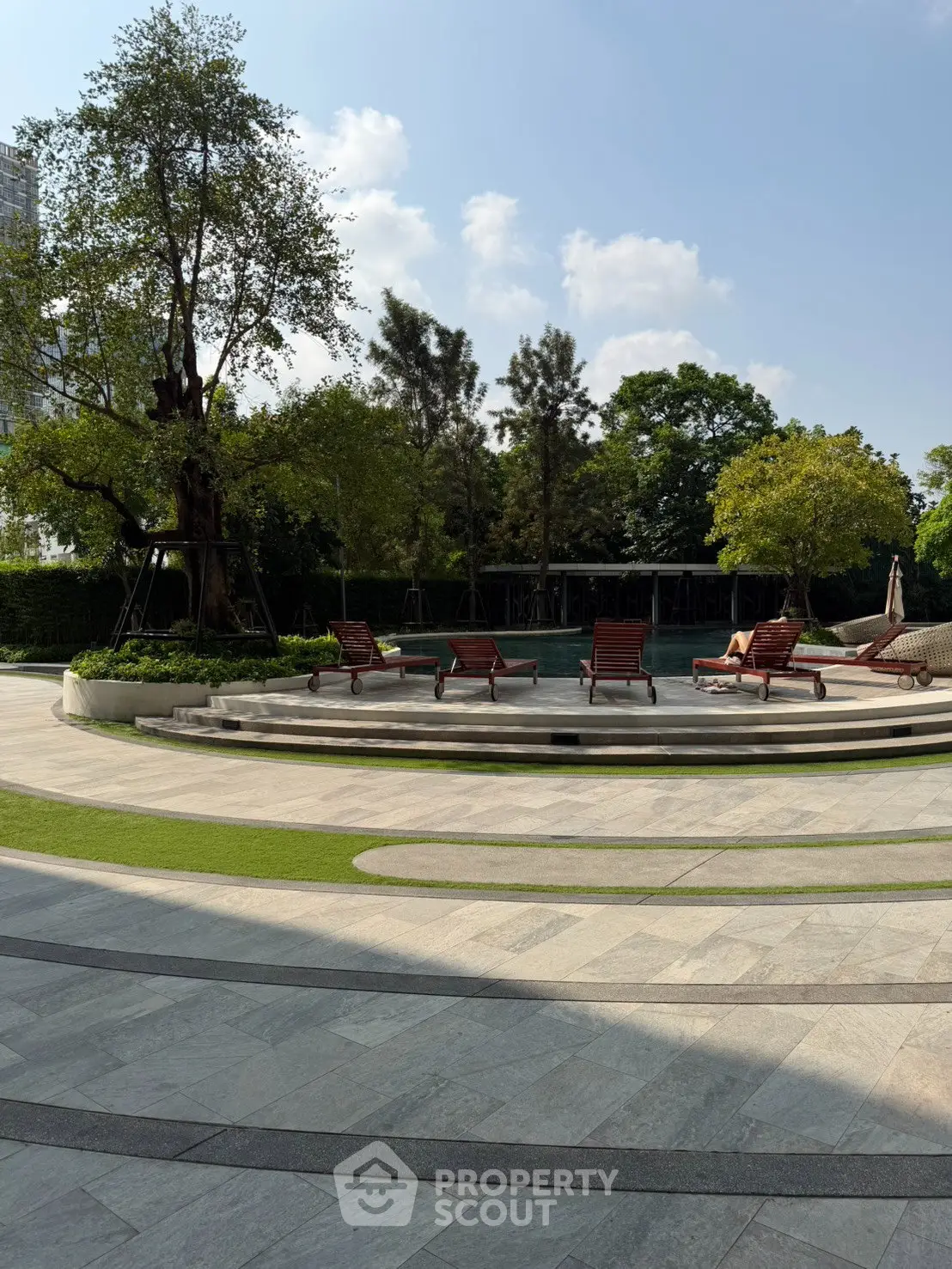 Luxurious outdoor pool area with sun loungers and lush greenery, perfect for relaxation and leisure.
