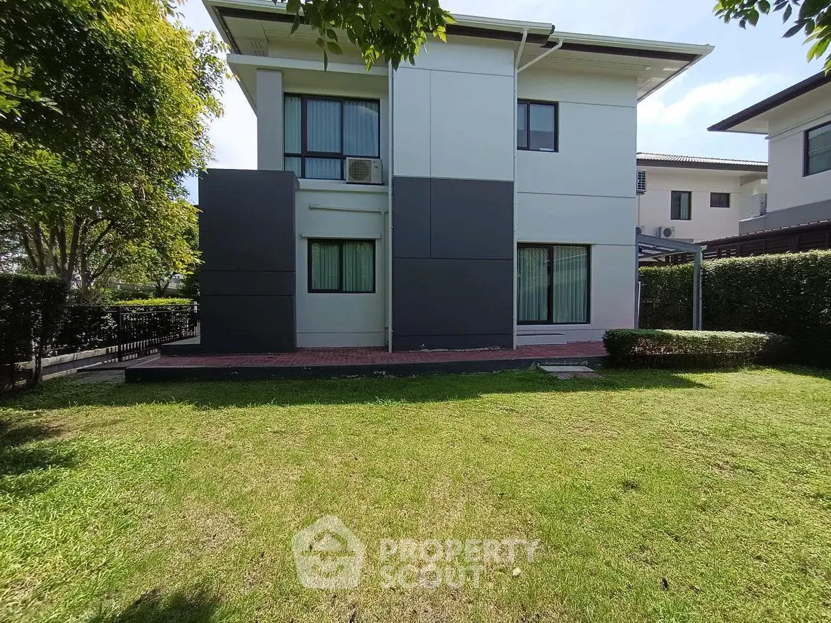 Modern two-story house with spacious green lawn and sleek exterior design.
