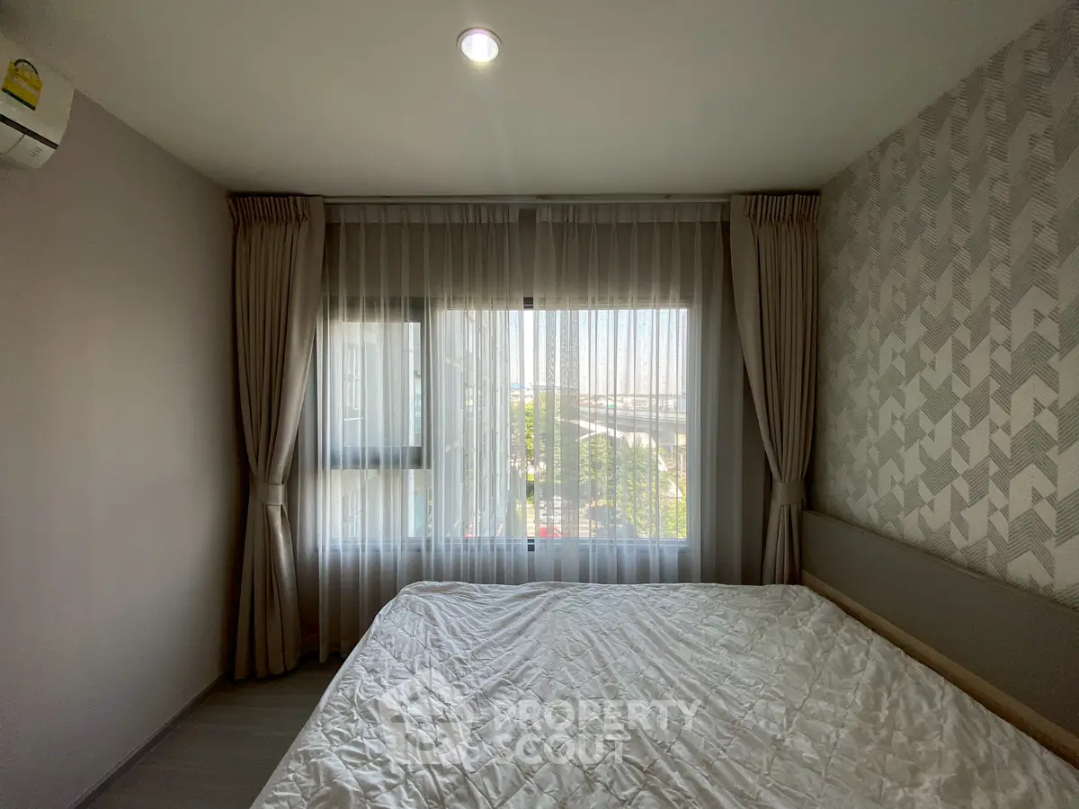 Cozy bedroom with large window and stylish curtains offering a serene view, perfect for relaxation.