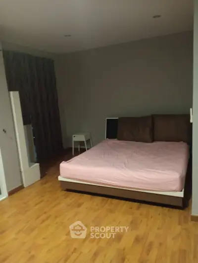 Spacious bedroom with wooden flooring and modern minimalist design.