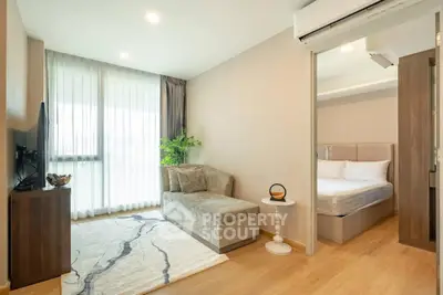 Modern living room with cozy sofa and bedroom view in open layout apartment
