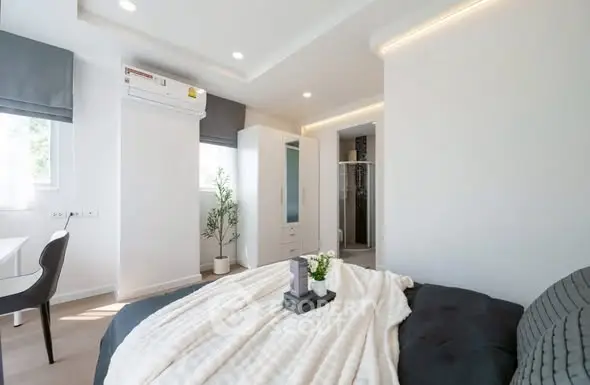 Modern bedroom with cozy decor and natural light, featuring a sleek air conditioning unit and stylish furnishings.