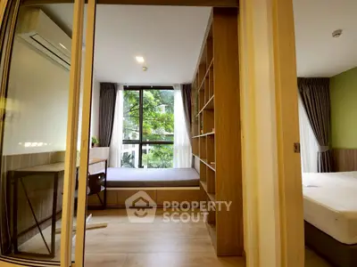 Modern bedroom with large window and built-in shelving, offering a serene view of greenery.