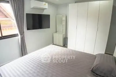 Modern bedroom with sleek design, featuring a large wardrobe and wall-mounted TV.