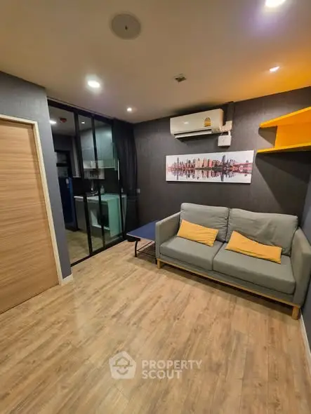 Modern living room with wooden flooring, cozy sofa, and stylish wall art in a contemporary apartment.