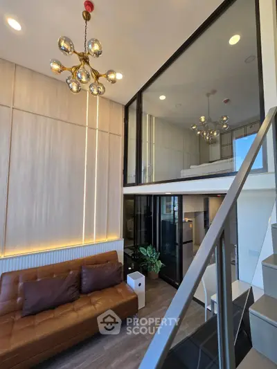 Modern loft apartment with stylish chandelier and cozy brown leather sofa