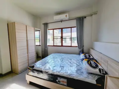 Spacious bedroom with large window and modern furnishings in a bright, airy apartment.