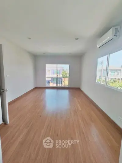 Spacious empty room with wooden flooring and large windows in modern apartment