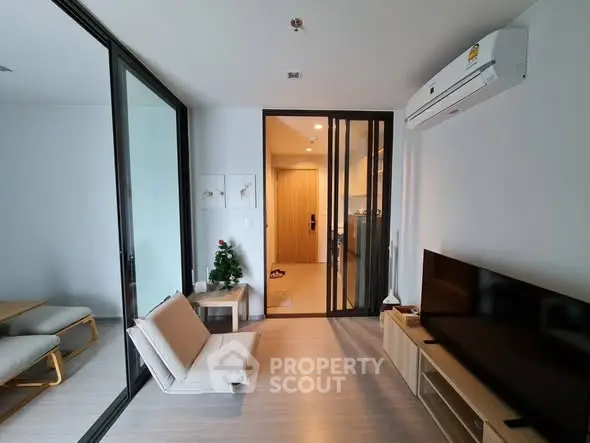 Modern living room with sleek furniture and open layout, featuring a cozy seating area and stylish decor.