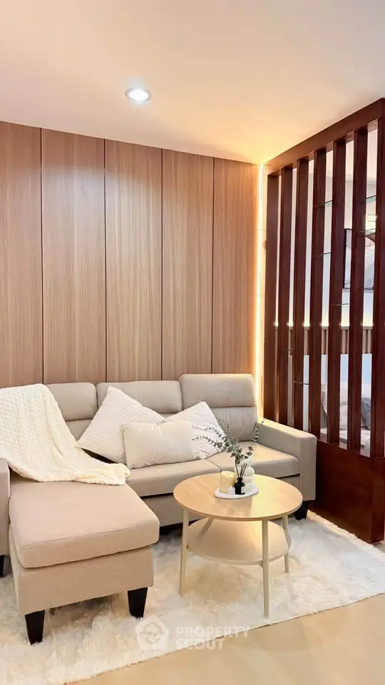 Cozy living room with modern beige sofa and wooden accent wall, perfect for relaxation.
