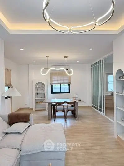 Modern living room with stylish lighting and open layout, featuring cozy seating and dining area.