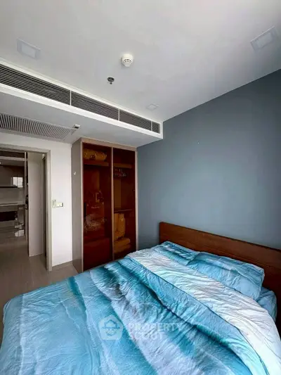 Modern bedroom with blue bedding and built-in wardrobe in a stylish apartment.
