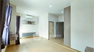 Spacious modern bedroom with wooden flooring and ample natural light