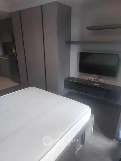 Modern bedroom with sleek furniture and wall-mounted TV, showcasing contemporary design.