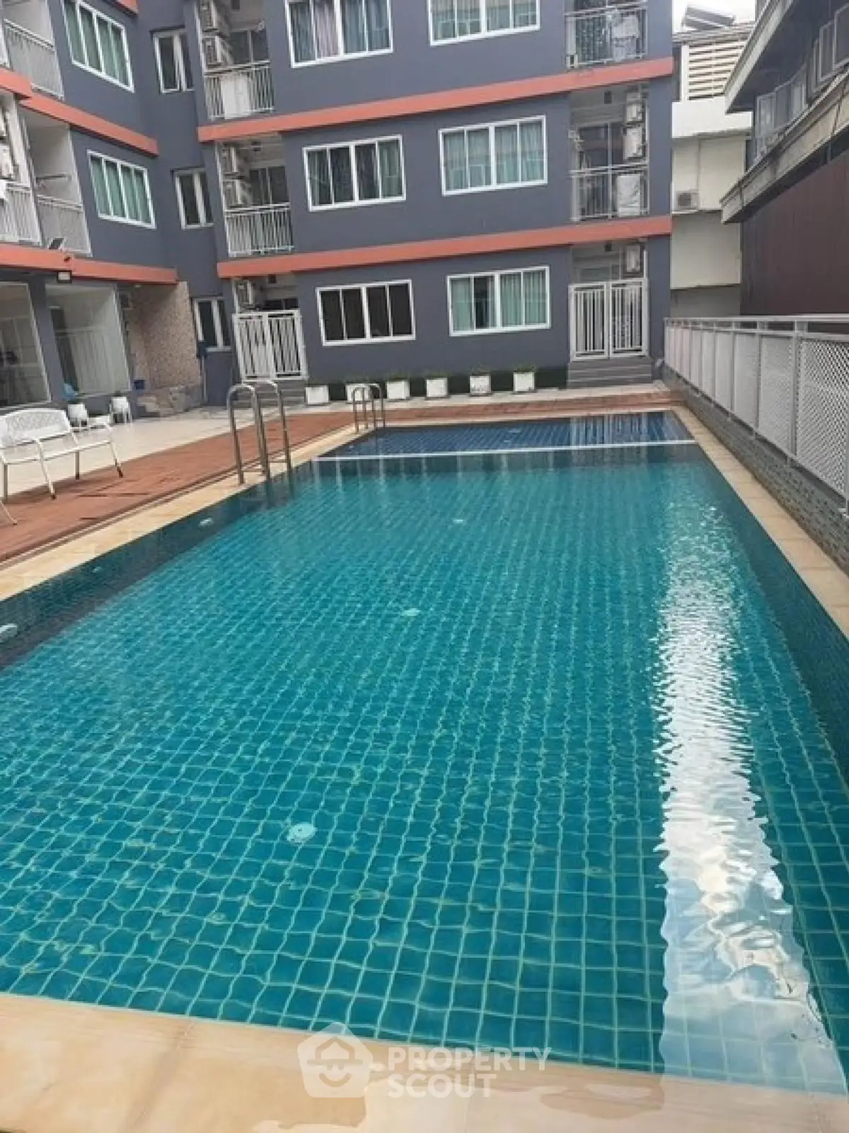 Modern apartment building with inviting swimming pool and spacious deck area.