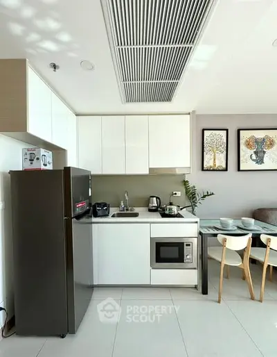 Modern kitchen with sleek appliances and dining area in a bright, stylish apartment.