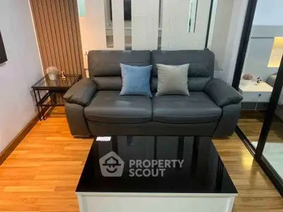 Modern living room with sleek black leather sofa and stylish wooden flooring