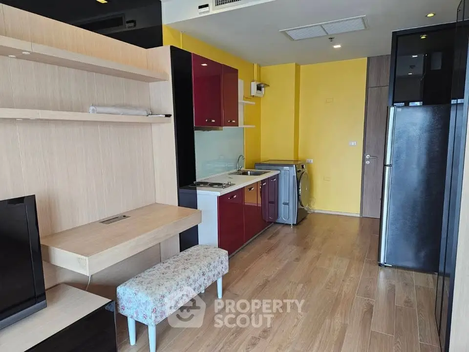 Modern studio apartment with vibrant yellow accent wall, compact kitchen, and cozy living area.