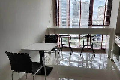 Modern dining area with city view, featuring sleek furniture and large windows.