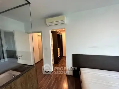 Modern bedroom with sleek wooden flooring and built-in closet, featuring a minimalist design and air conditioning.