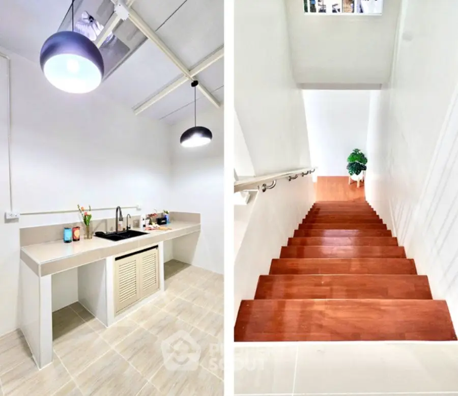 Modern kitchen with sleek design and wooden staircase leading to upper floor.
