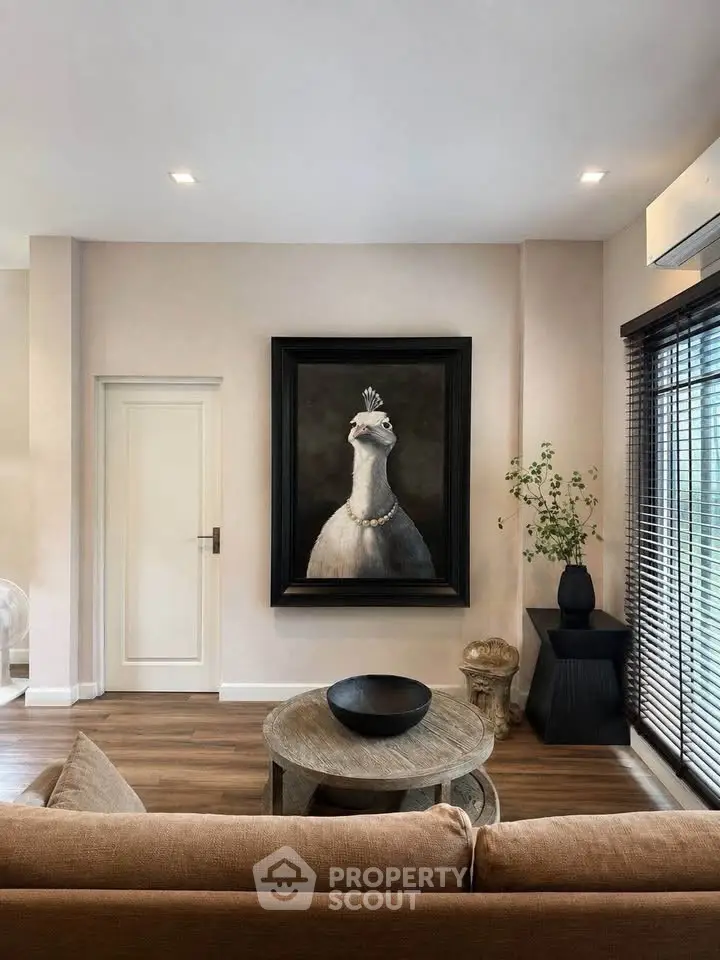 Stylish living room with elegant decor and unique peacock artwork, featuring modern furniture and natural light.
