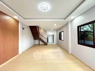Spacious modern living room with wooden accents and staircase, ideal for family gatherings.