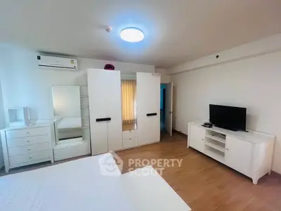 Spacious bedroom with modern white furniture and wooden flooring