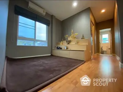 Cozy bedroom with polished wooden floors, large window allowing natural light, and a dedicated space for personal decor or a study area.