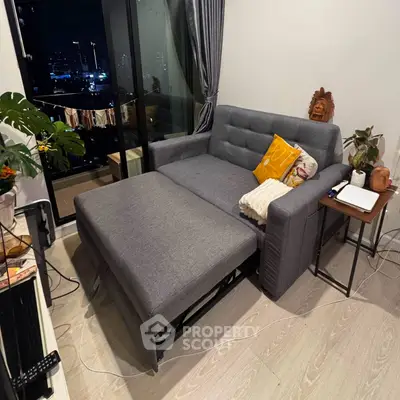 Modern living room with a stylish gray sofa bed and balcony view, perfect for urban living.