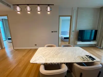 Modern dining area with marble table and stylish lighting in open-plan apartment.