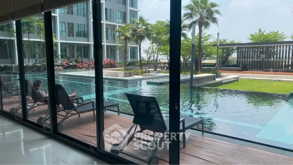 Luxurious poolside view with modern apartment backdrop and lush greenery, perfect for relaxation and leisure.