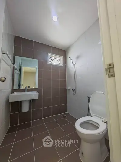 Modern bathroom with sleek design and neutral tiles, featuring a shower and toilet.