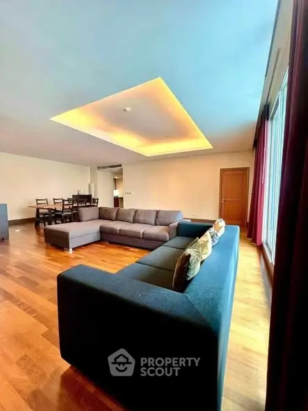 Spacious modern living room with large sectional sofa and dining area, featuring elegant wooden flooring and ambient lighting.