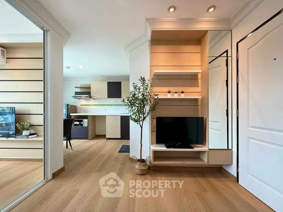 Modern open-plan living room with stylish wooden flooring and built-in TV unit