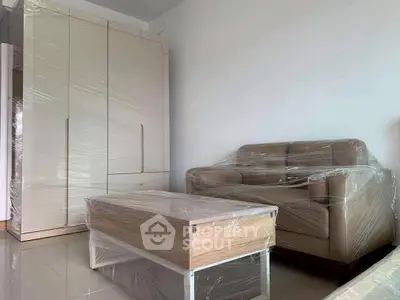 Modern living room with wrapped furniture and sleek wardrobe, ready for move-in.