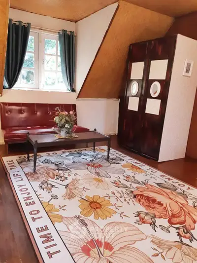 Charming attic living room with floral rug and vintage decor, perfect for cozy relaxation.